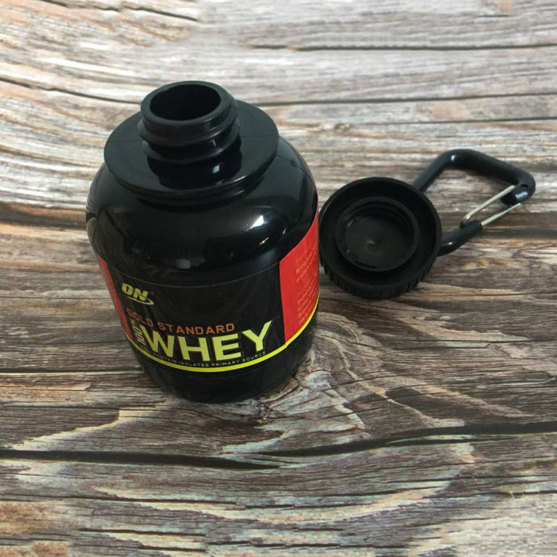 Black protein powder container with a carabiner on a wooden surface