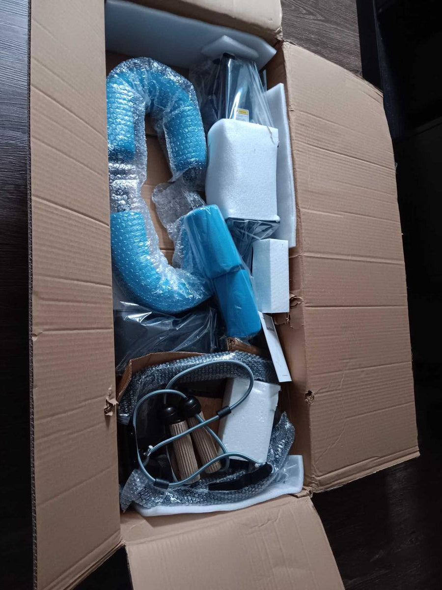 Open cardboard box with electronic components wrapped in bubble wrap and plastic on a dark surface.